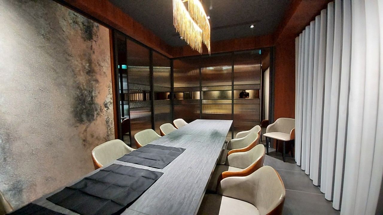 商業包廂以現代與個性工業風格呈現，結合仿鏽蝕斑駁特殊漆牆面與黑色金屬長虹玻璃隔屏，搭配長型餐桌與流蘇吊燈，形塑沉穩內斂的用餐氛圍。