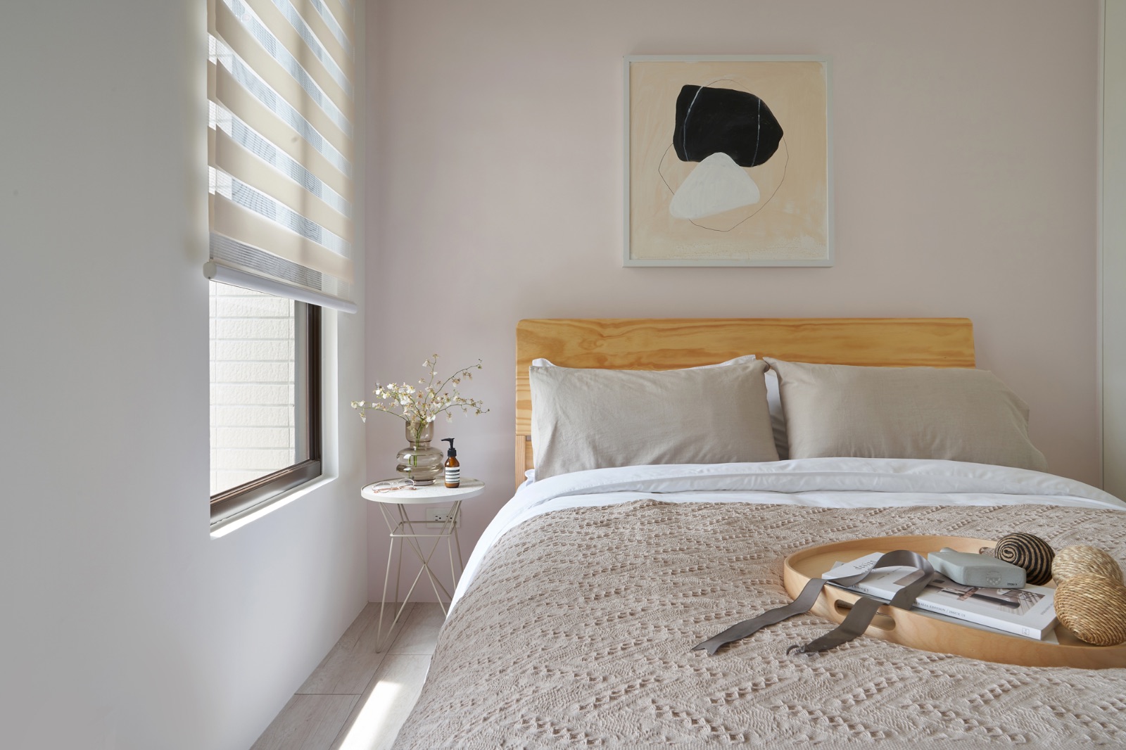 臥室以北歐自然風格鋪陳，粉膚米杏色牆面搭配淺原木床頭板與棉麻床品，窗邊配置調光簾引進自然光線，營造純淨簡約的睡眠空間。